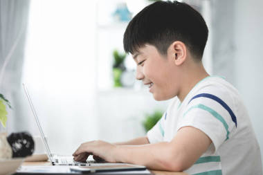 亞洲可愛男孩使用筆記本電腦