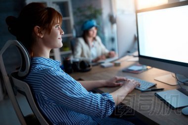 現代休閑女設計師在工作場所微笑和加班
