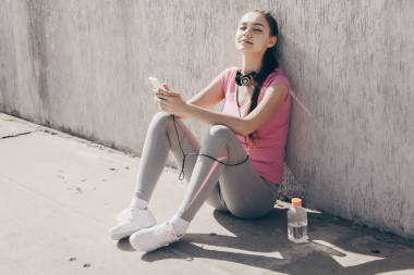 迷人的女孩運動員在粉紅色的 t恤坐在地面上的太陽, 獲得的力量和能量