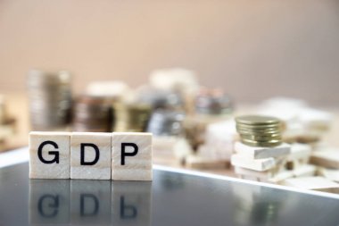 在木立方體中書寫的 Gdp 詞在黑色 mirrow 上的反射以貨幣棧為背景圖