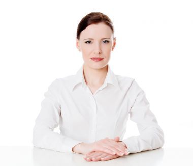 坐在白色的表的年轻商业女人肖像