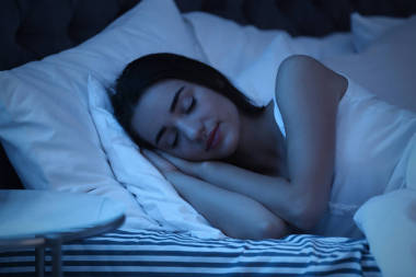 晚上睡在床上的年輕女子。睡眠時間