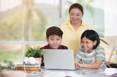 亞洲教師和兒童使用筆記本電腦娛樂