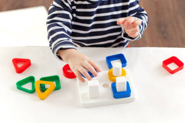 15歲的孩子坐在桌前玩著一個發(fā)展中的玩具, 蒙臺梭利技術(shù), 孩子的手正忙著玩