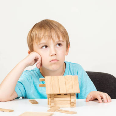 小男孩梦想着回家。孩子们从木制积木里建造小房子。聪明的孩子创造建筑。梦见甜蜜的家。家庭观念。童年和教育游戏