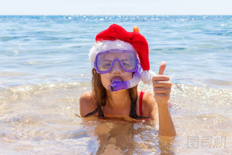 美麗的年輕女子與浮潛設備和圣誕帽在海邊