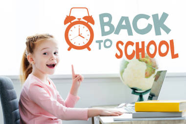 這個(gè)紅頭發(fā)的孩子一邊在家里用書(shū)本和筆記本電腦學(xué)習(xí)，一邊寫(xiě)著“返?！钡男藕汪[鐘，一邊對(duì)著鏡頭微笑