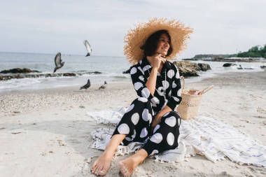 婦女在暑假穿著草帽和海灘禮服享受風(fēng)景在海