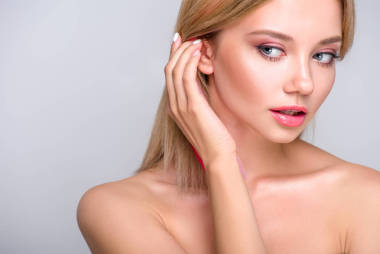 特写肖像的美丽的年轻女子把头发背后的耳朵孤立的灰色