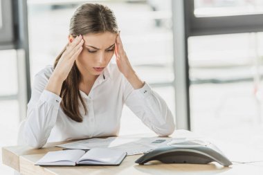 困惑的年輕女商人在辦公室做文書工作