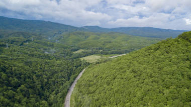 在俄罗斯索契的森林里, 沿着蜿蜒的山路行驶的汽车的空中股票照片。人行, 路之旅, 穿越美丽的乡村风光