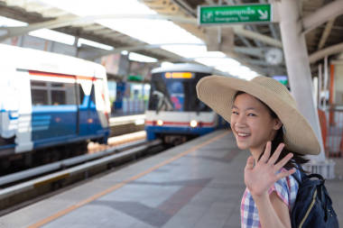 亞洲逗人喜愛(ài)的女孩在去輕軌車(chē)站旅行之前感覺(jué)幸福在大城市的旅行, 生活方式和運(yùn)輸概念