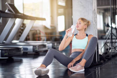 在健身房里喝瓶裝水的快樂女性肖像