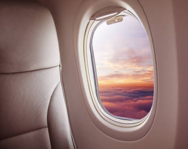 飛機(jī)內(nèi)部與窗口視圖日落在云彩之上。旅行和空運概念