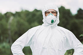 微笑的男性科学家在防护面具和西装看户外摄像机的选择性聚焦 