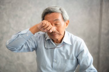 資深男子手持眼鏡, 揉他疲憊的眼睛, 而閱讀電子書在平板電腦