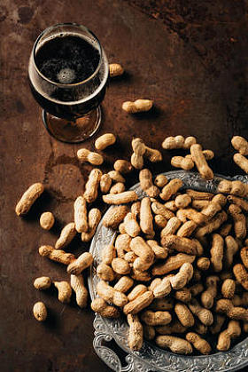 锈桌上金属托盘上的冷啤酒和花生杯的顶部视图