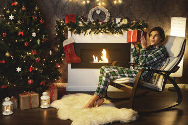 圣誕節(jié)或新年慶祝。坐在壁爐邊的搖椅上的快樂女人