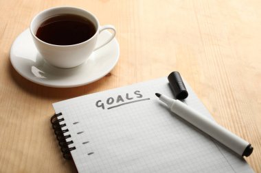 記事本與目標和一杯茶在木質(zhì)背景