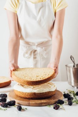 裁剪拍攝的女人做美味的分層蛋糕白色