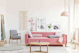 图案扶手椅旁边的粉红色沙发在公寓内部与海报和木桌。真实照片