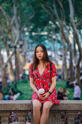 穿着红色连衣裙的年轻女子坐在街上喝着咖啡