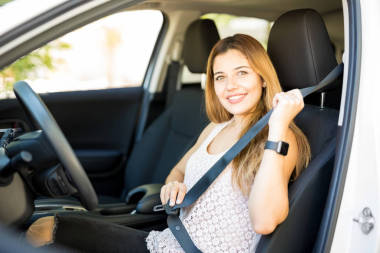 可愛的年輕女子的肖像把她的安全帶, 然后開車離