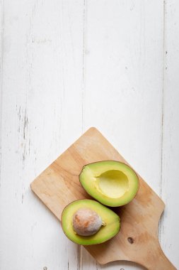 新鲜有机鳄梨切成白色木桌的一半