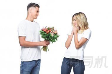 側(cè)面的男朋友呈現(xiàn)花束驚訝的女朋友在白色孤立