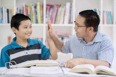 一個亞洲男性教師的肖像做高五與他的學(xué)生一起學(xué)習(xí)在圖書館