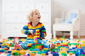 孩子玩着五颜六色的玩具积木。小男孩在家或日间关心大厦塔。幼儿教育玩具。婴儿或学步儿童的建筑砌块。幼儿园游戏室一团糟