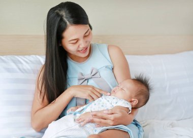 母亲在床房里抱着熟睡的婴儿