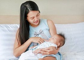 母亲在床房里抱着熟睡的婴儿