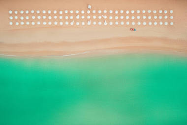 空中的頂視圖，在海灘上。遮陽傘、 沙灘和大海的波浪