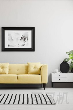 海報(bào)上面的黃色沙發(fā)在最小的灰色客廳內(nèi)部與地毯和櫥柜。真實(shí)照片