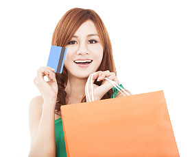 微笑的年轻女士持有信用卡的购物袋