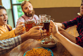 The concepts of people, leisure, friendship and communication -- happy friends drinking beer, talking and matchless glasses in a bar or tavern