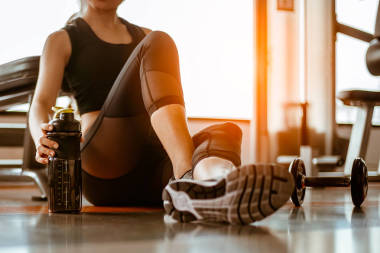 訓(xùn)練后放松。漂亮的年輕女子坐在體育館里看著別處。年輕女子在體育館里休息