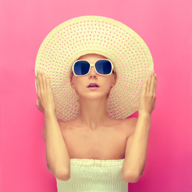 一個(gè)女孩在粉紅色的背景上的一頂帽子的肖像