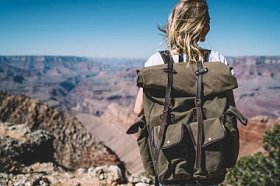 带背包的女性旅行者的背景色探索美国的本性徒步旅行, 时髦的女孩从山砂岩形成看大峡谷的美丽的风景