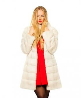 快乐美丽的年轻金发女郎在白貂皮毛皮大衣。在白色背景上被隔离