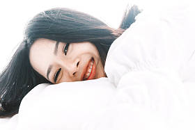 美丽的女人在床上放松在她的房间在家