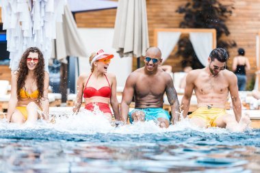 一群年輕快樂的朋友在游泳池里休息