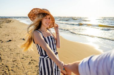 在沙灘上散步時, 微笑的女人抱著男友手的部分看法
