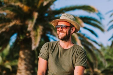 年輕男子站在棕櫚樹看太陽圖片