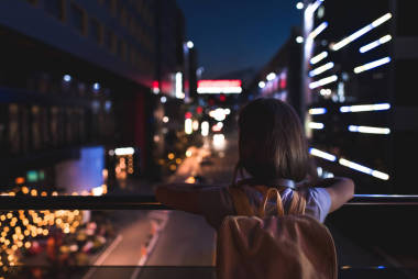 后面的婦女與背包站在街上, 看夜城燈
