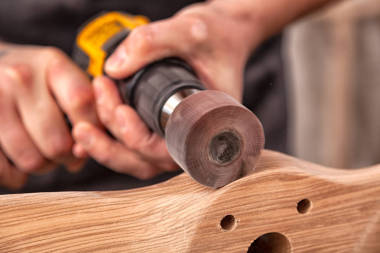 關(guān)閉一個(gè)年輕的男子建設(shè)者木匠等于拋光木板與打磨機(jī)或隨機(jī)軌道砂光器在車間