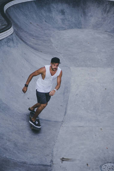 一個時髦的年輕人穿著白色 t恤, 在 skatepark 的滑板上溜冰, 在游泳池里滑冰