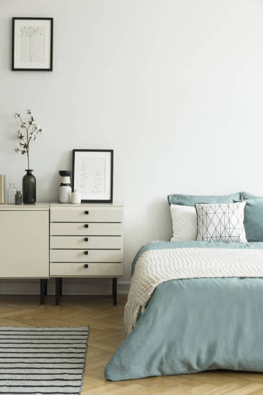 海報(bào)和內(nèi)閣與植物在白色臥室內(nèi)部與毯子在綠色床上。真實(shí)照片