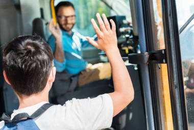 在上車時(shí), 小學(xué)生向快樂公交車司機(jī)招手的后視